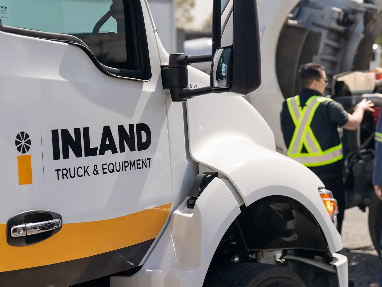 An Inland Truck & Equipment service repair truck parked near a semi-truck requiring service.