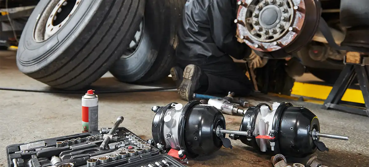 A heavy-duty truck mechanic replacing the brake chambers on a semi-truck.